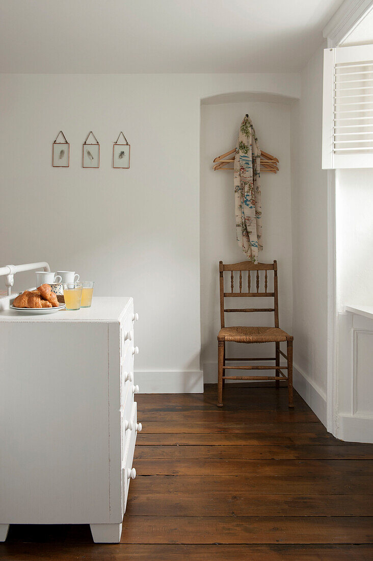 Wooden clothes hangers above wicker chair in alcove of Cornwall bedroom UK