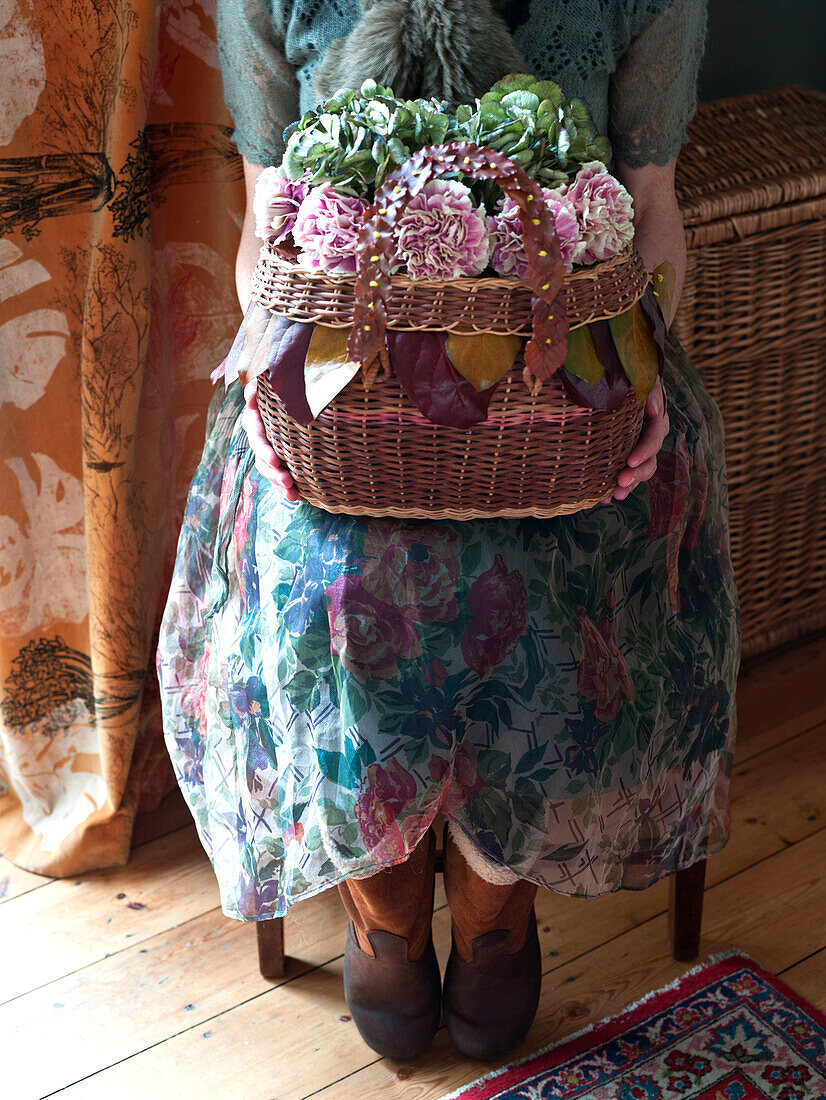 Woman holds basket of Autumn flowers in UK home