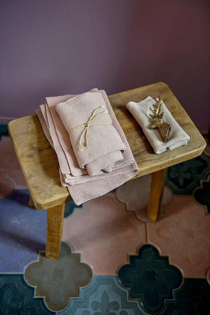 Face towels on wooden stool with tiled floor in London bathroom UK