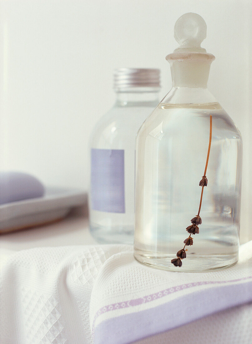 Lavender toiletries in clear bottles on a towel in the bathroom 