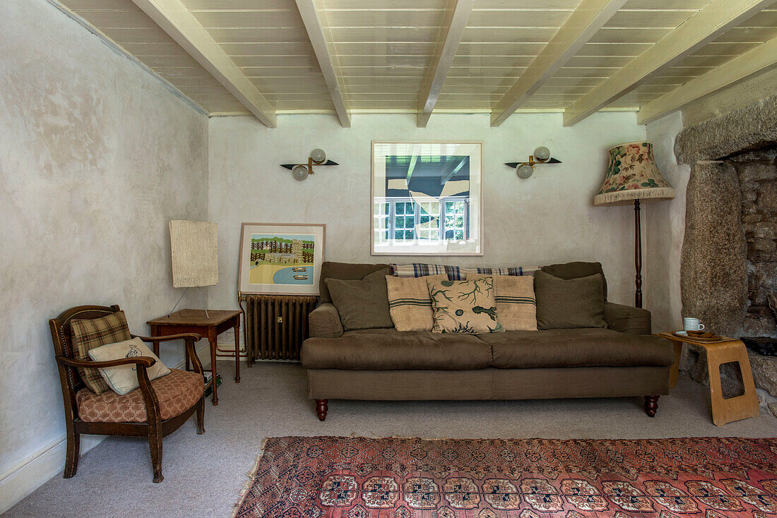 Brown sofa with floor lamp and cushions in Helston farmhouse living room Cornwall UK