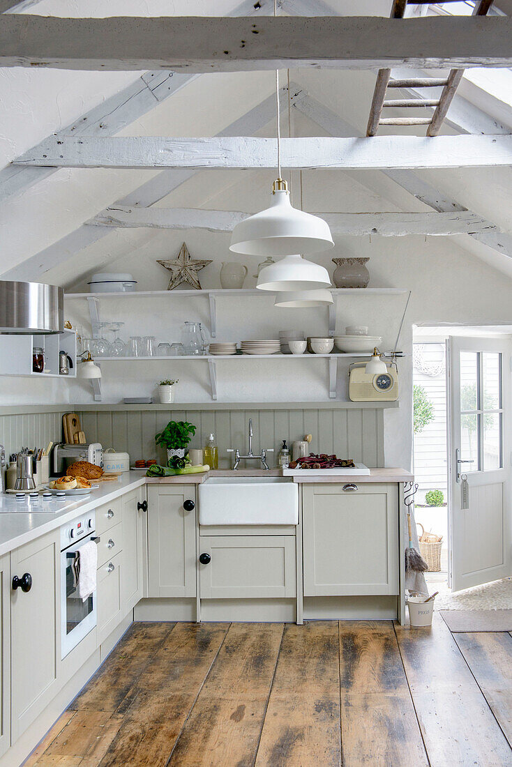 Tableware on shelving under beamed attic kitchen in Marazion beach house Cornwall UK