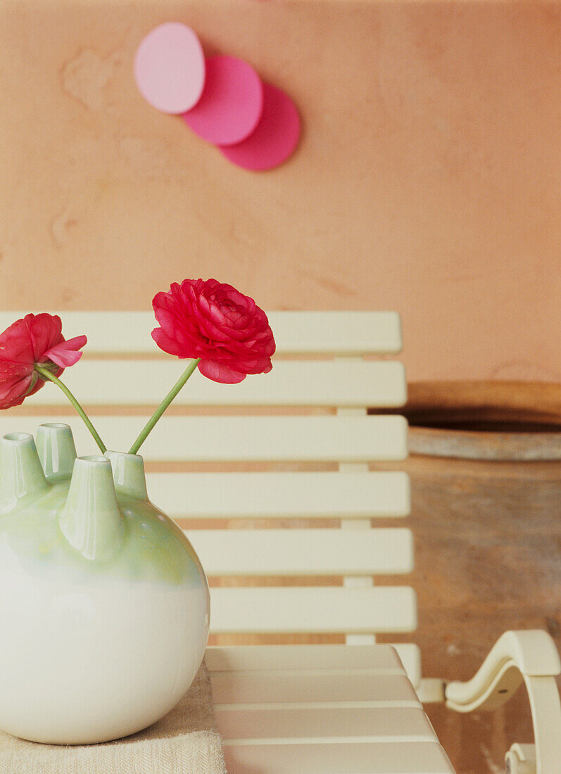 Gartentisch und -stühle mit einer Vase mit frischen Blumen auf der Terrasse