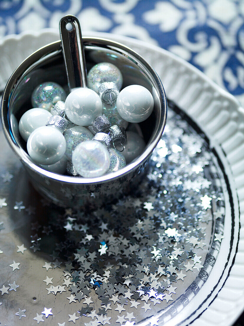 White baubles in metal bucket with star confetti