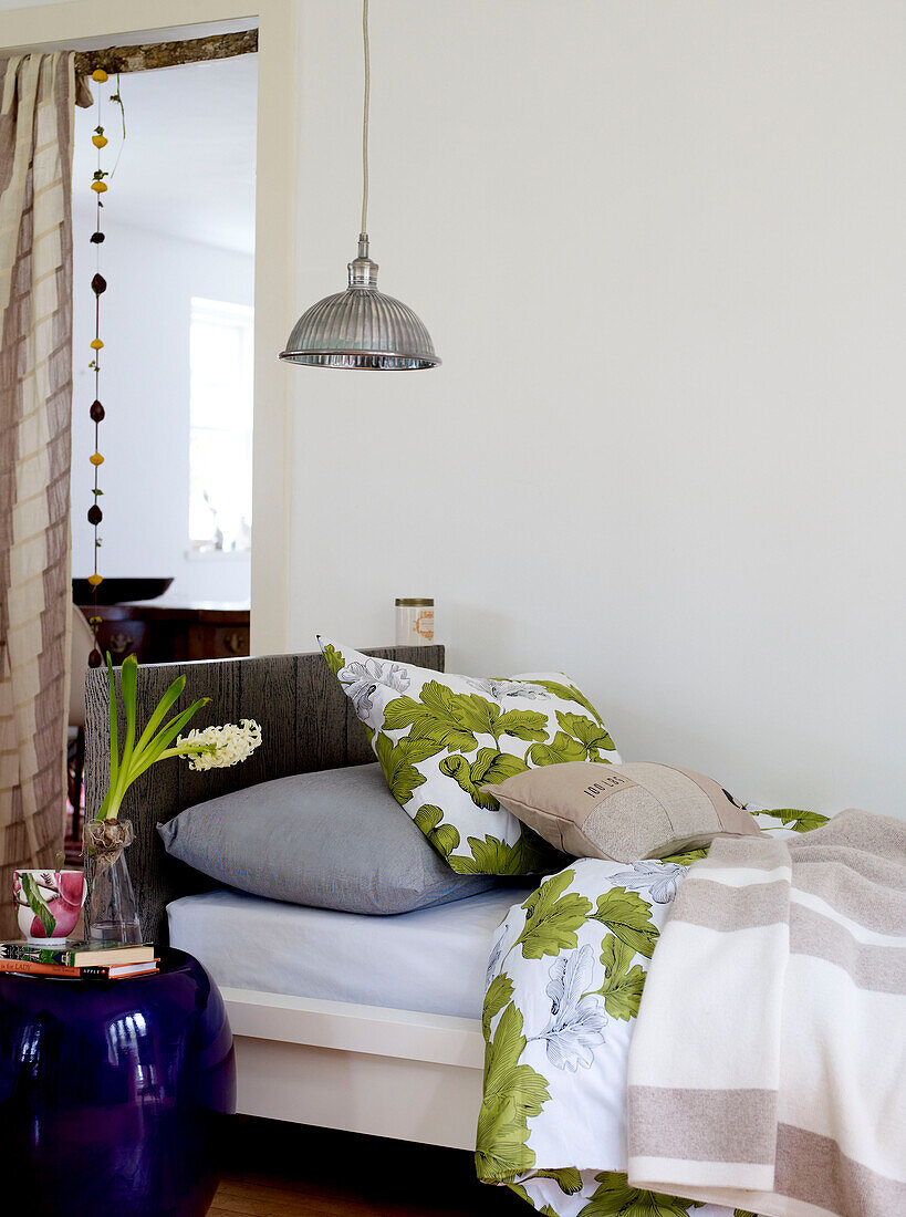 Metal pendant above single bed with foliate pillow and duvet