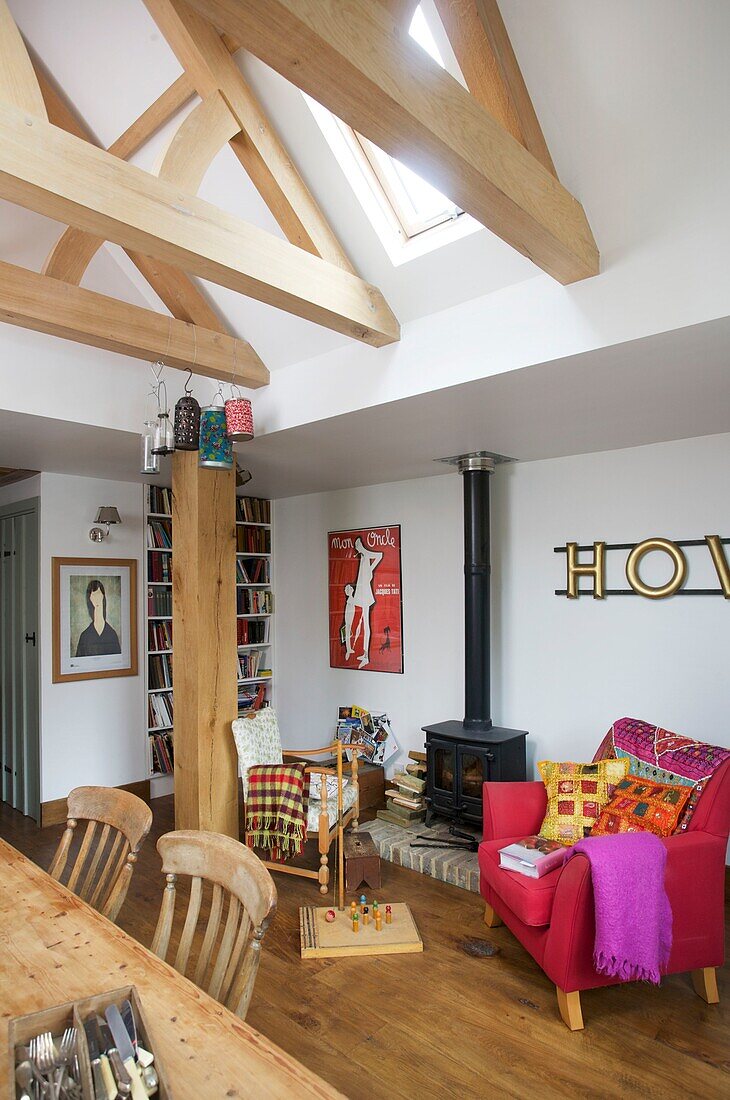 Pink armchair in open plan dining area of Cranbrook family home with beamed pitched ceiling, Kent, England, UK