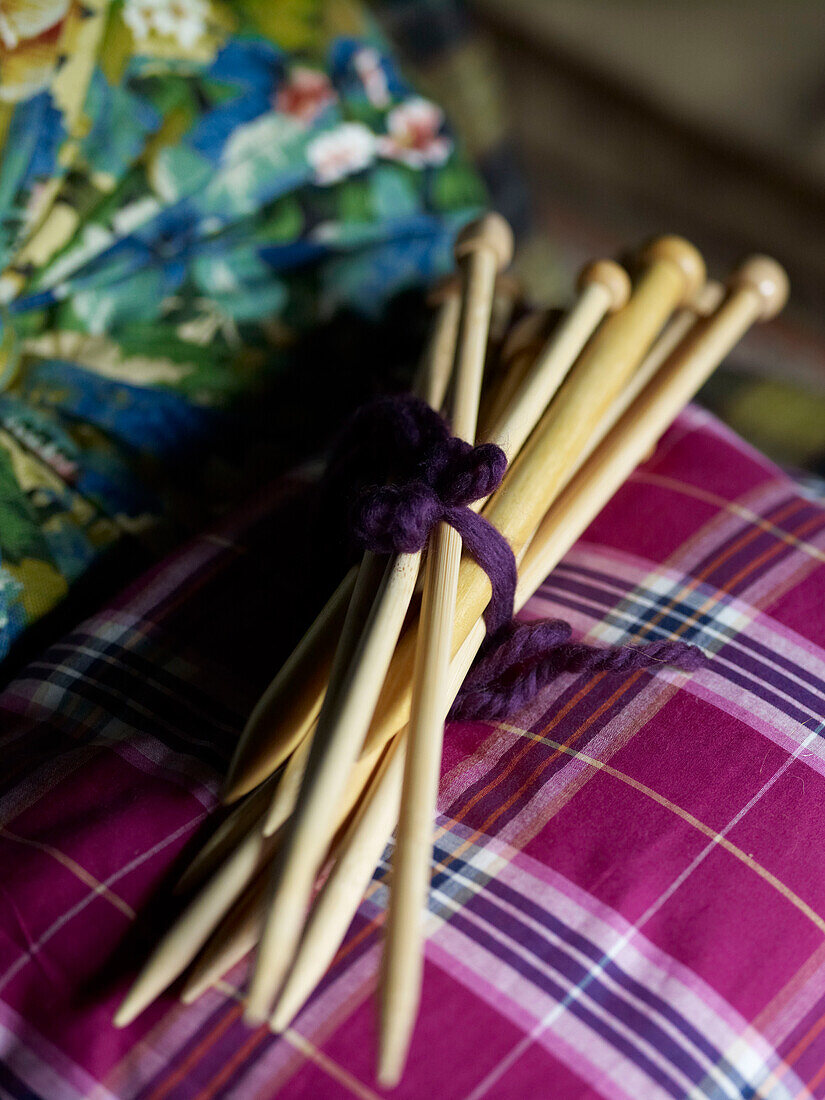 Bündel von Stricknadeln auf rosa Tartan