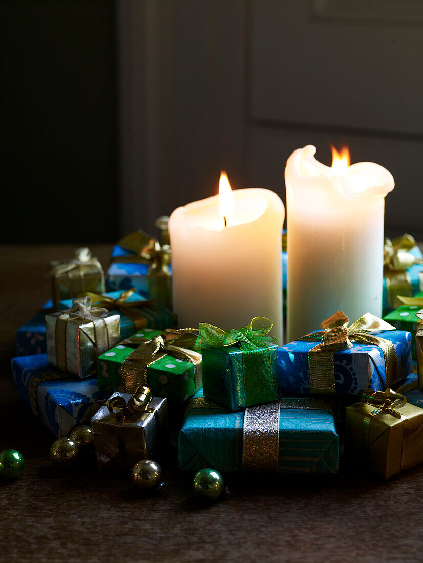 Angezündete Kerzen mit einer Gruppe von kleinen Geschenken und Kugeln