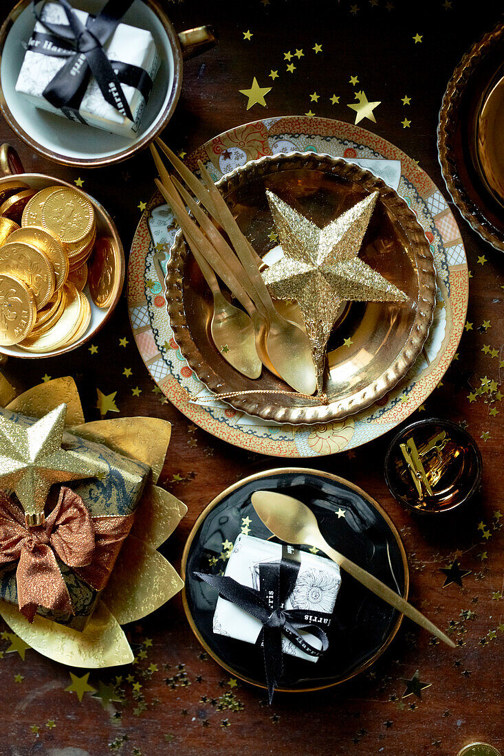 Chocolate coins and gold star with spoons and gifts on table