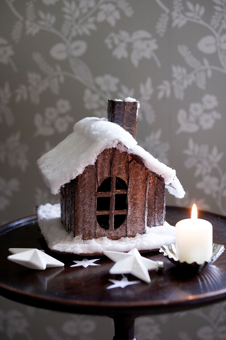 Model cabin and lit candle on antique wooden side table