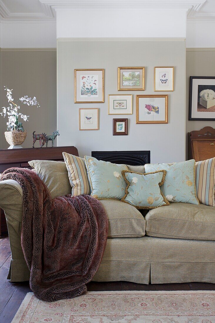 Pelzdecke auf dem Sofa im Wohnzimmer mit Kunstwerken in einem Haus in Cranbrook, Kent, England, UK