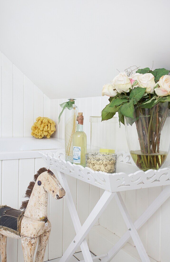 Rocking horse and cut yellow roses in bathroom of Cranbrook home, Kent, England, UK