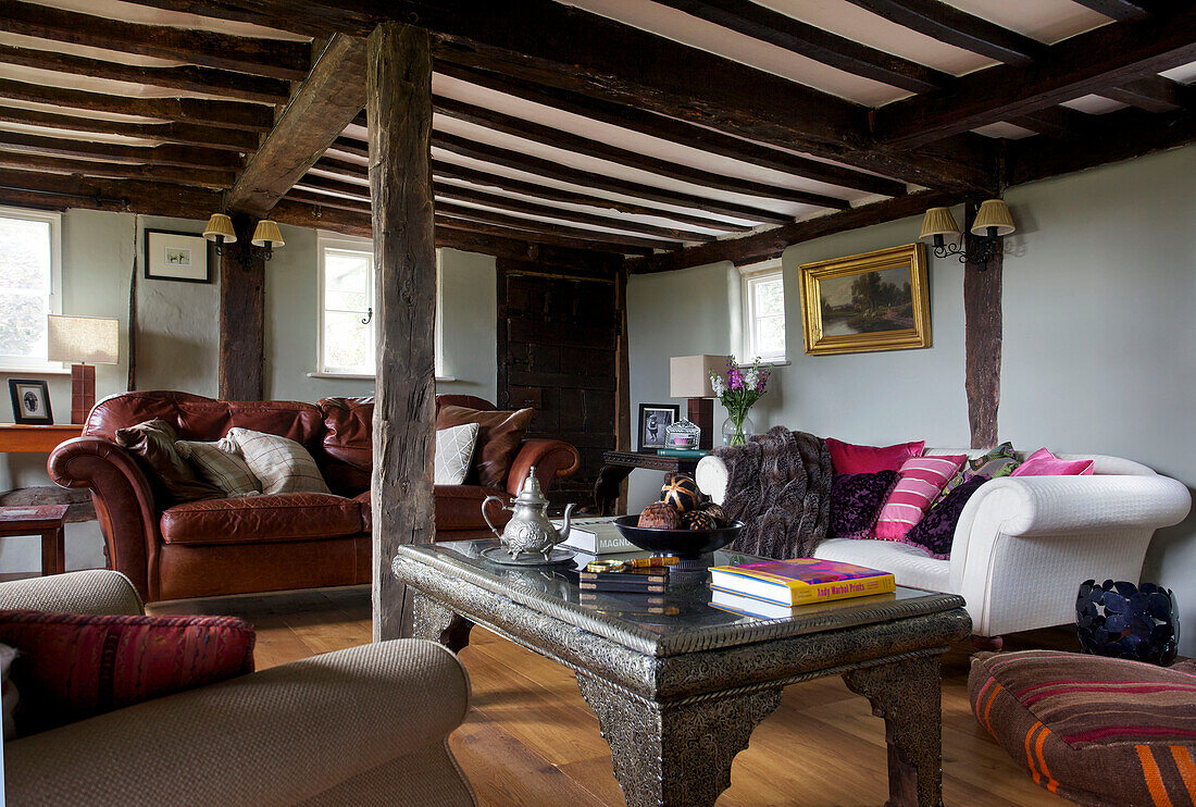 Brown leather sofa and metalworked coffee table in beamed living room in Sandhurst cottage, Kent, England, UK