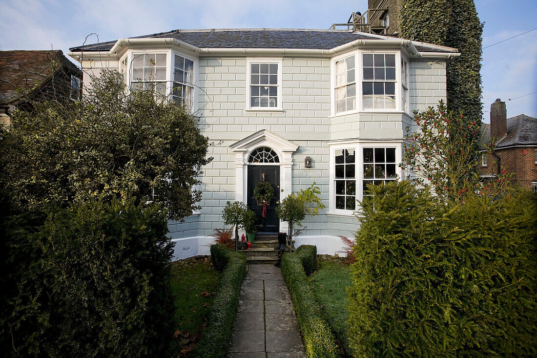 Bemalte Außenfassade eines Hauses in Tenterden mit Weihnachtskranz an der schwarzen Haustür, Kent, England, UK