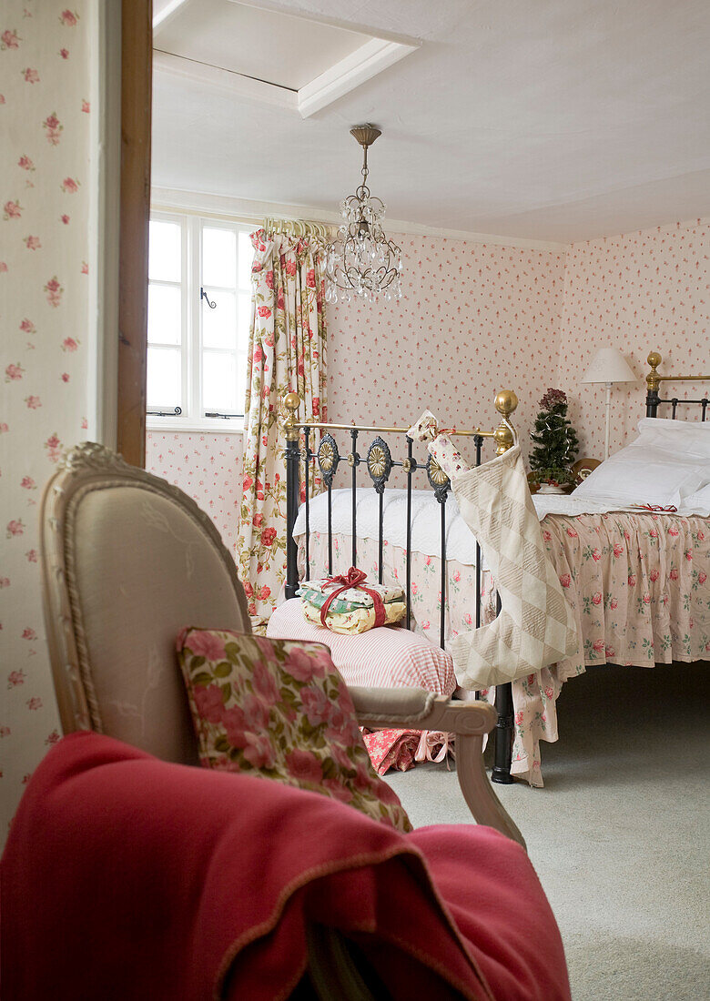 Armchair and blanket with Christmas stocking hanging on brass bed in Tenterden home, Kent, England, UK