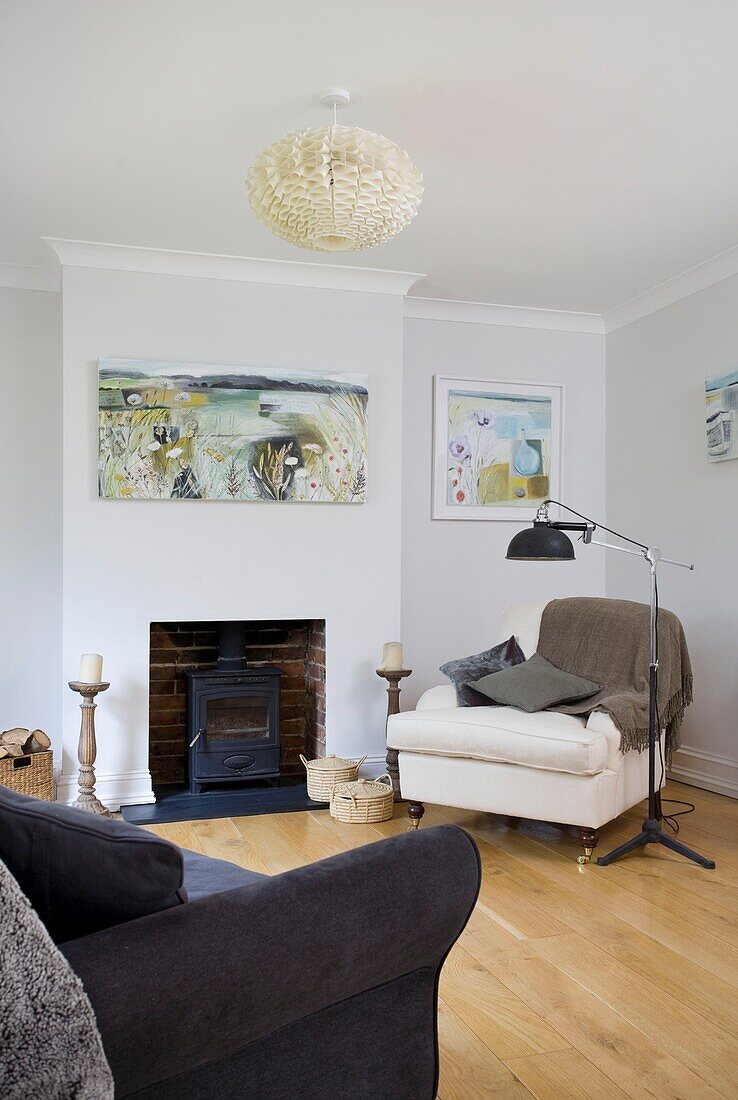 Armchair at fireplace with artwork in Tenterden family home, Kent, England, UK