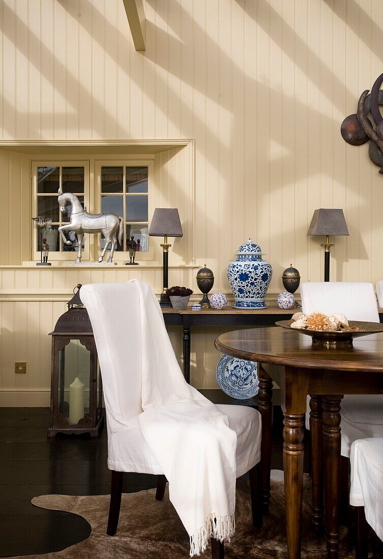 Slip-covered dining chairs in conservatory extension of timber framed cottage, Grafty Green, Kent, England, UK