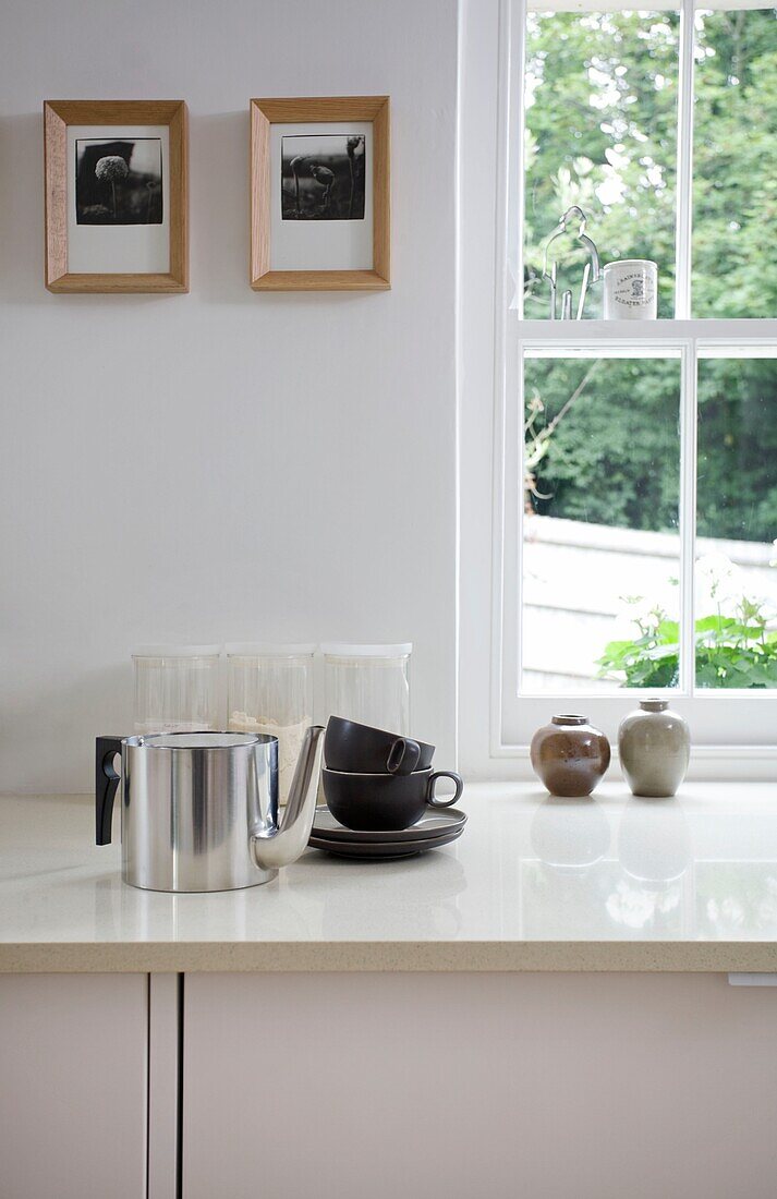 Teekanne und Tassen aus Metall auf der Arbeitsplatte am Fenster in einem Fachwerk-Cottage
