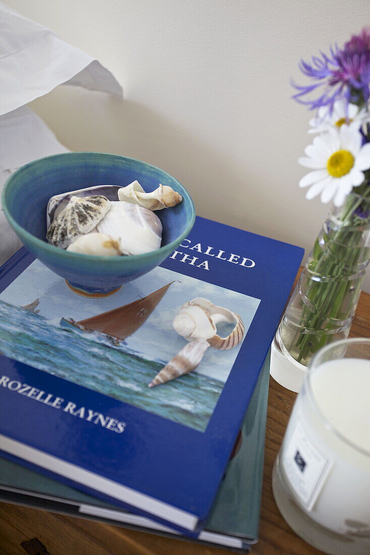 Muscheln in einer Schale mit Duftkerze und Büchern in einem Haus in Dartmouth, Devon, UK