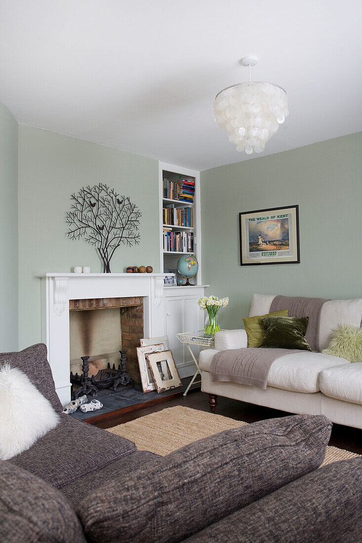 White and grey sofas in light green living room with tree ornament on fireplace in Deal home Kent England UK