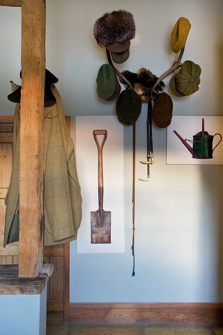 Flatcaps on antlers with artwork in hallway of Etchingham farmhouse East Sussex England UK