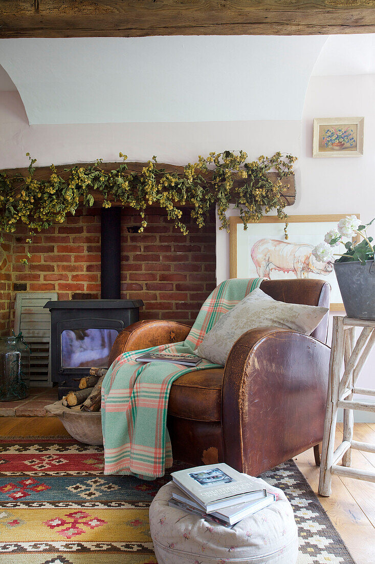 Braunes Ledersofa am Kamin mit Holzofen in High Halden Bauernhaus Kent England UK