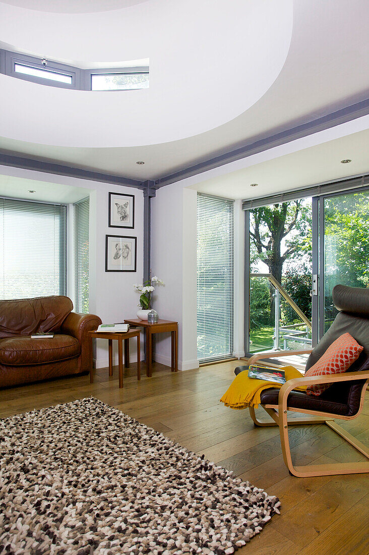 brown leather sofa and armchair with rug in living room of Rolvenden water tower conversion Cranbrook Kent England UK