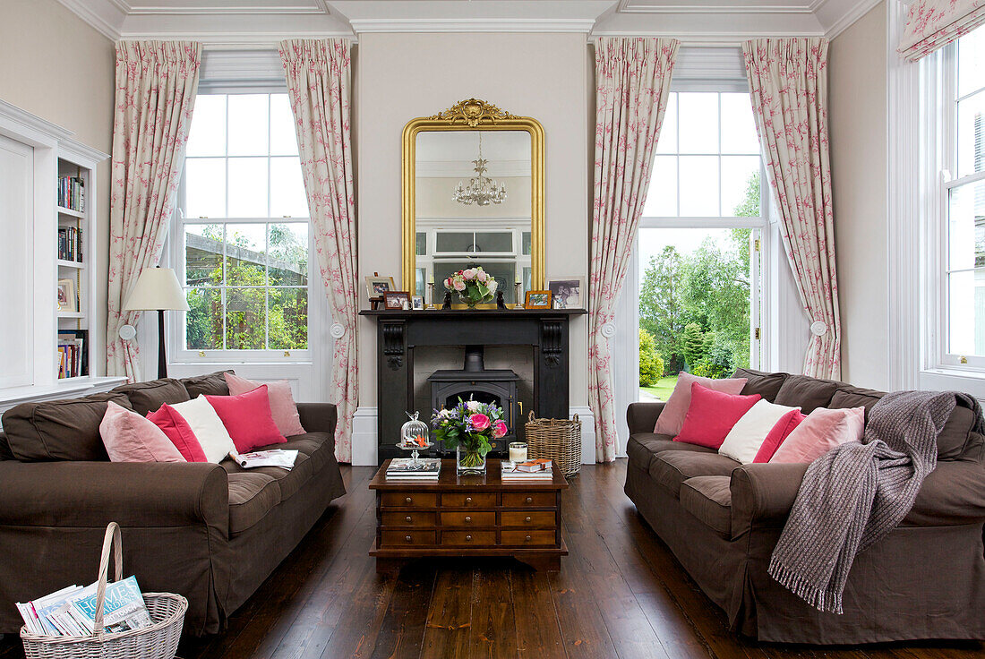 Pink cushions on sofas with wooden coffee table drawer unit in in living room of Kilndown home Cranbrook Kent England UK