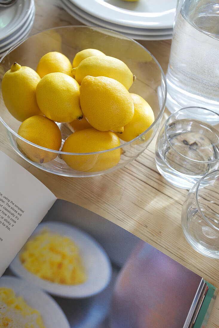 Schale mit Zitronen und Rezeptbuch auf dem Tisch im Haus in Smarden, Kent, England, Vereinigtes Königreich