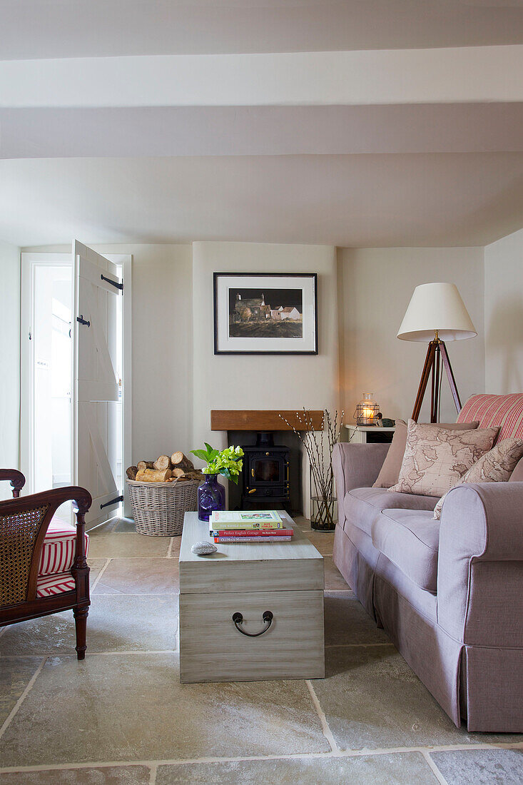 Lilac sofa and blanket box with fireplace in Dorset cottage Corfe Castle England UK