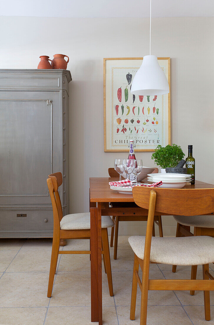 Wooden table and chairs with artwork and painted storage cupboard in Old Town dining room Portsmouth England UK