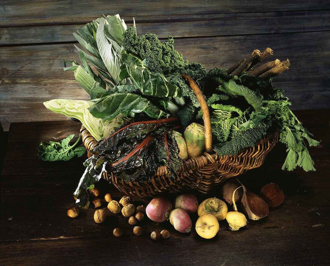 Several cabbages, turnips & leafy vegetables in basket, nuts