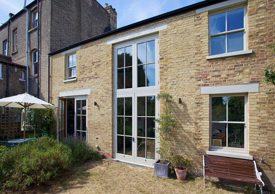 Parasol in back garden with double height doorway and brick exterior Hackney home London England UK