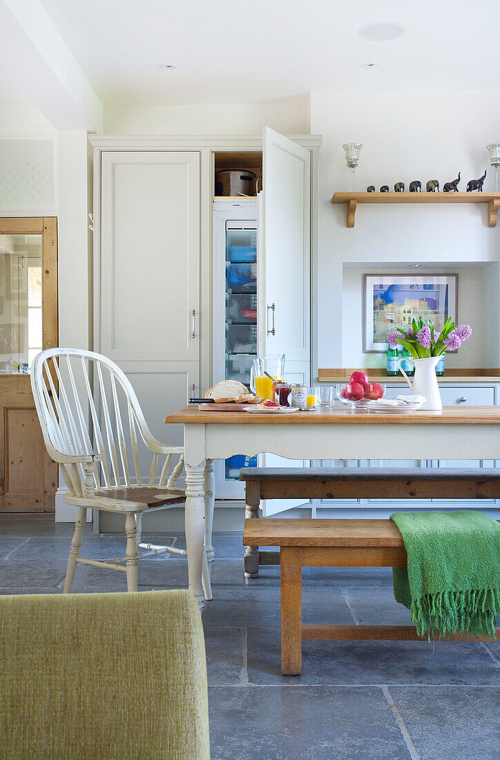 Painted white chair at table in open plan kitchen of Woodchurch home Kent England UK