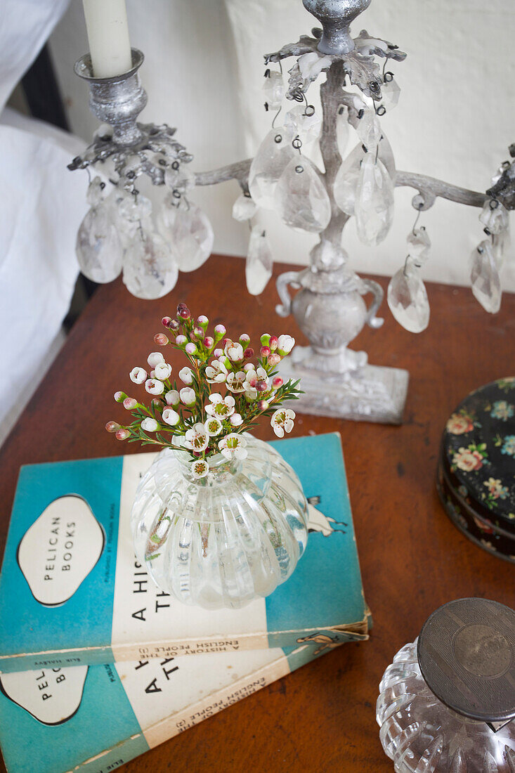 Schnittblumen und Taschenbücher mit Kerzenständer auf dem Nachttisch in einem denkmalgeschützten Bauernhaus in East Sussex aus dem 17
