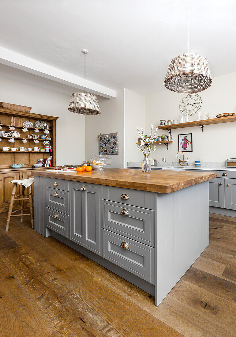 Wicker pendants above kitchen island with oak wood dresser in Warehorne rectory Kent UK