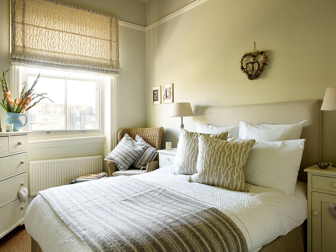 Striped blanket on double bed in room with roman blinds at window in Kensington home London England UK