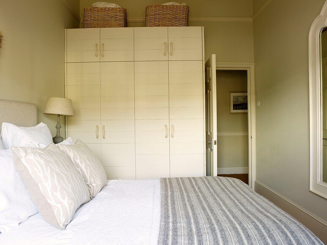 Striped blanket on bed with white storage unit in bedroom of Kensington home London England UK