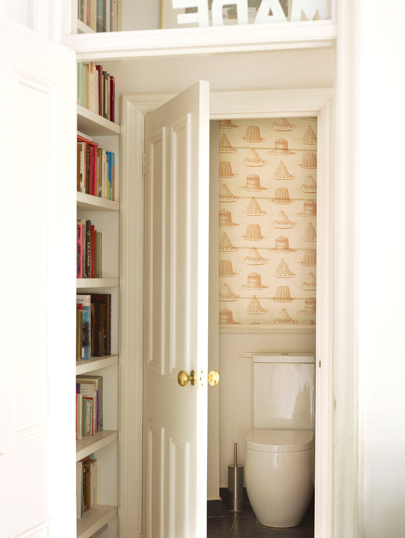 Bookshelf with view into cloakroom in London home England UK