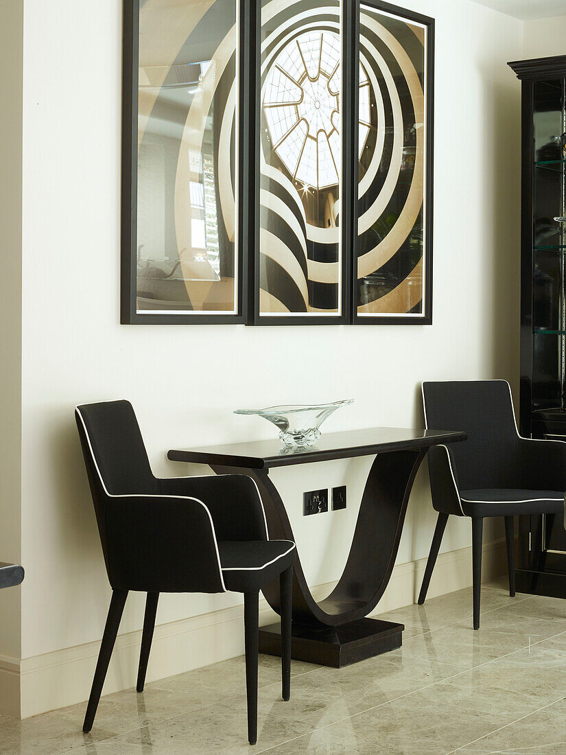 Pair of black upholstered chairs with artwork and console in London townhouse, UK