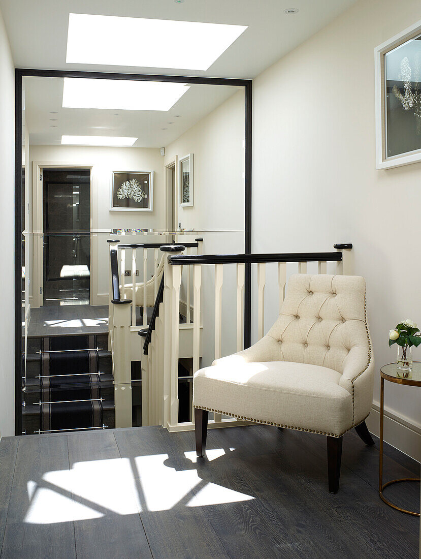 Buttoned armchair in mirrored staircase landing of London townhouse, UK