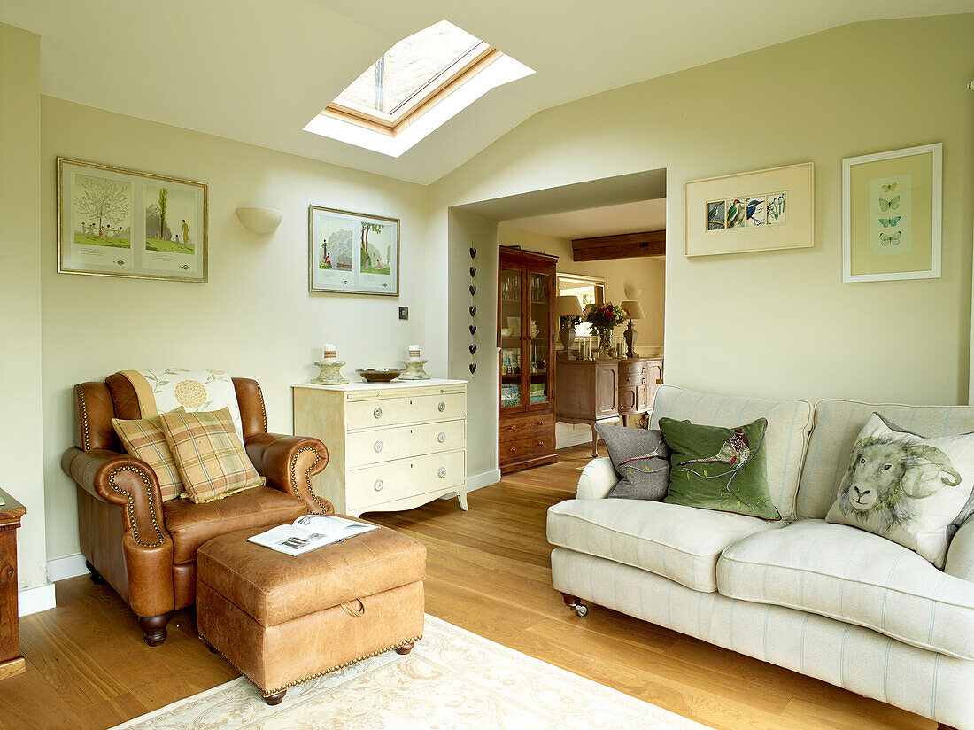 Brown leather armchair and footstool with sofa in modernised Oxfordshire cottage, England, UK