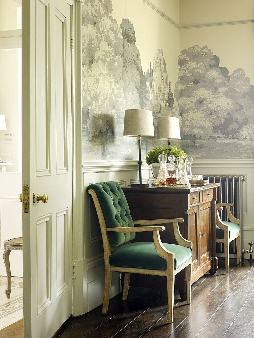 Matching lamps on wooden sideboard with wall frieze in dining room of East Sussex country house England UK