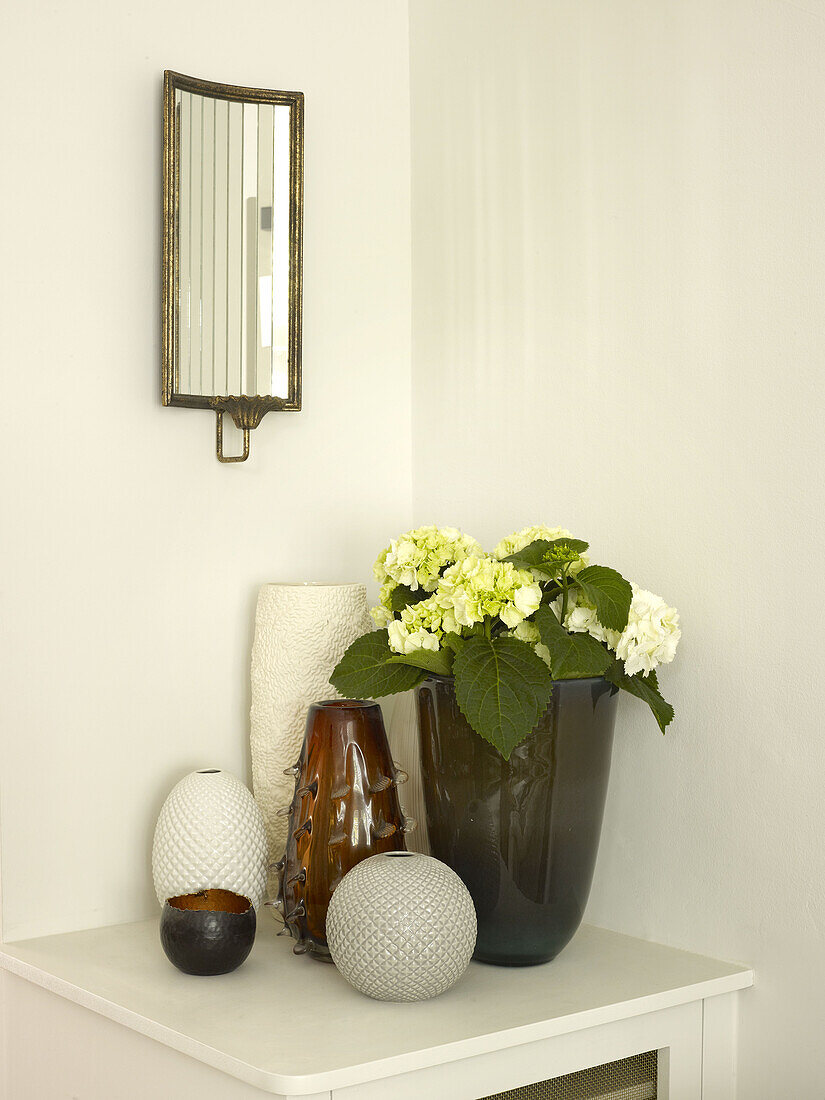 Schnittblumen und Vasen mit Vintage-Spiegel auf einem Beistelltisch in einem Stadthaus in Nordlondon, England, UK