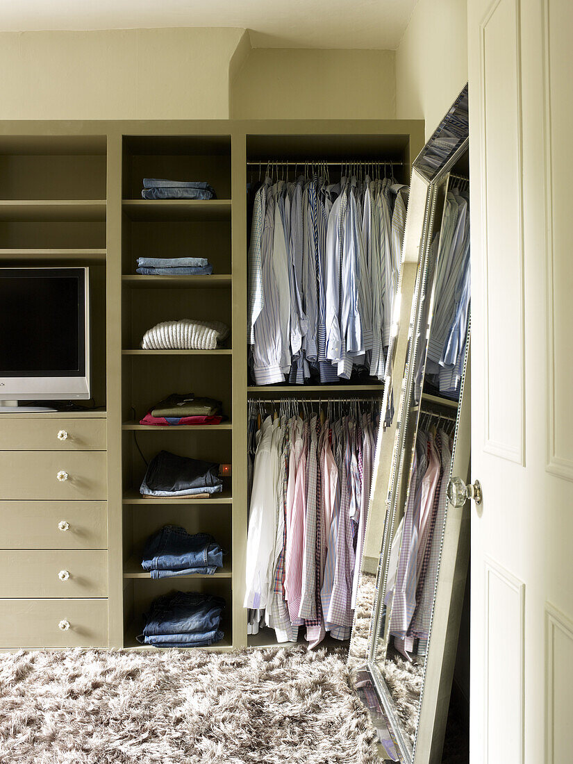 Hemden und Blusen in einem Schlafzimmerschrank mit Spiegel in voller Länge in einem Stadthaus in Nordlondon, England, UK