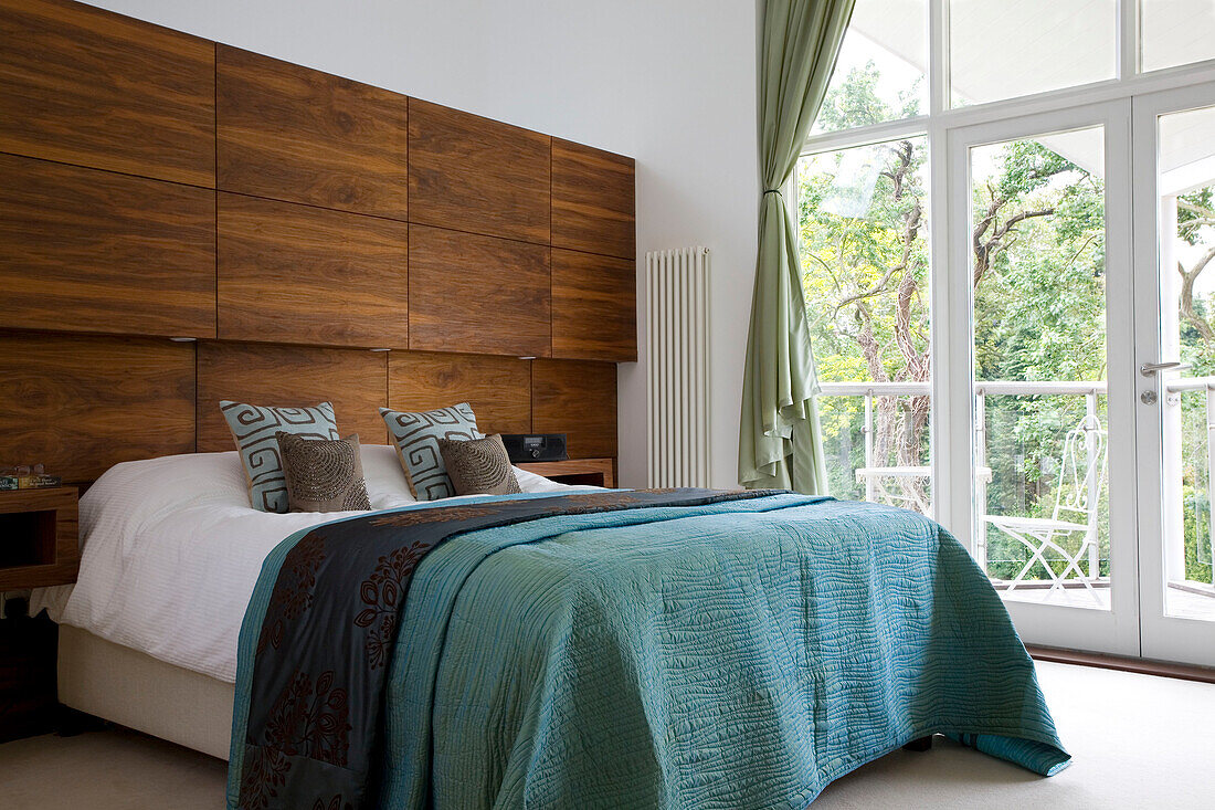 Turquoise bedspread with oversized wooden headboard in Cambridgeshire home UK