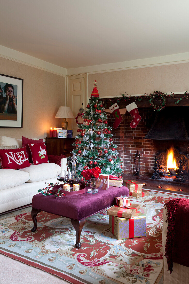 Christmas gifts and drinks on ottoman footstool with festive decoration in Kent home, England, UK