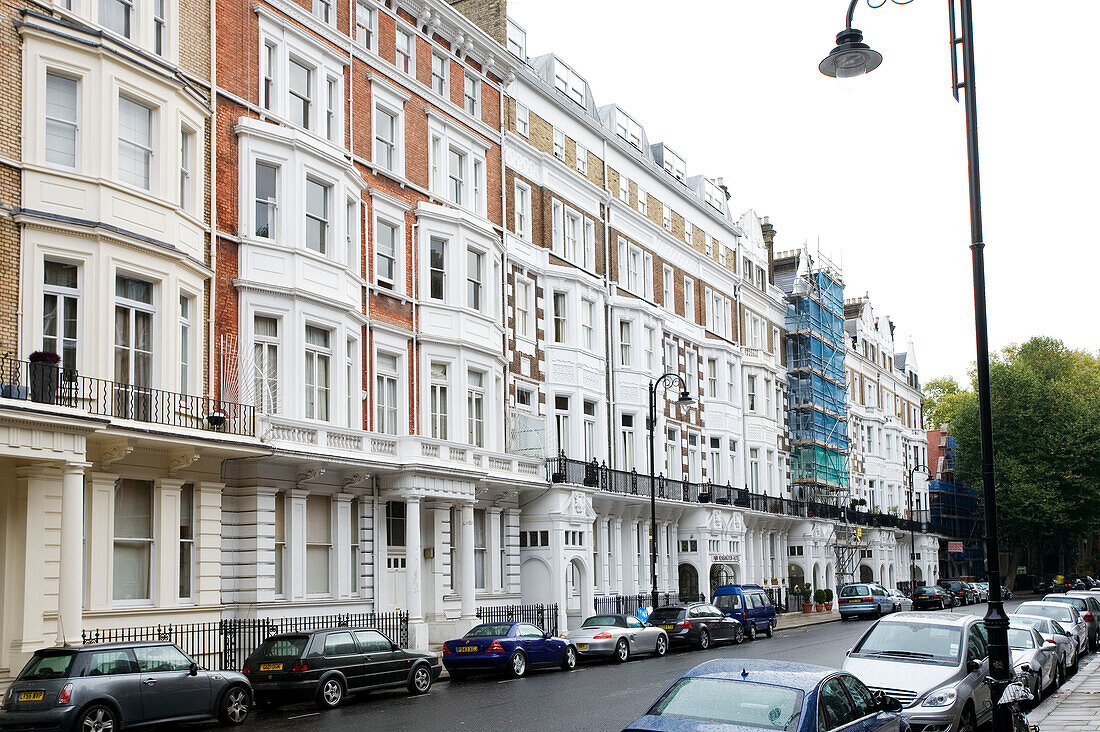 Cars parked in the street outside terraced townhouses