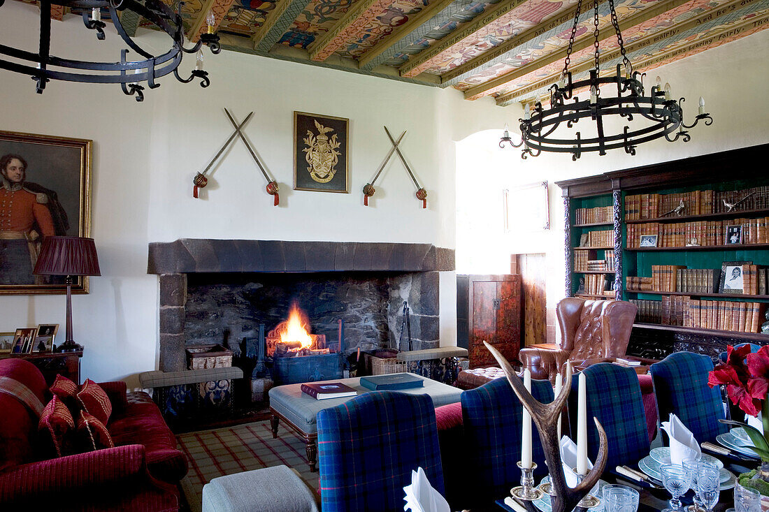 Bookcase and swords with lit fire in Scottish home UK