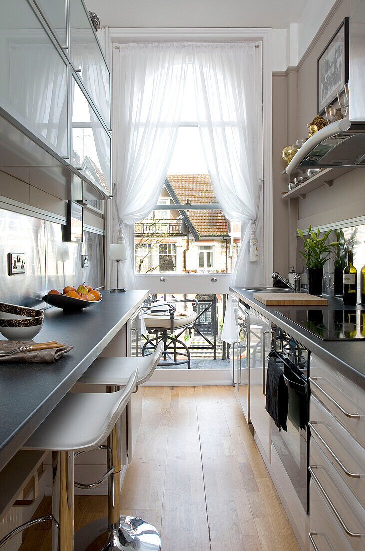 Narrow galley kitchen with white net curtains Hove East Sussex UK